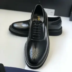 Black leather derby shoes, pair on a white surface